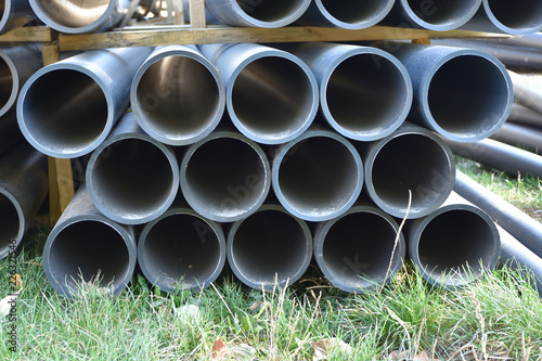 Stack Of Black Plastic Water Pipes On A Green Gr Closeup Stack Of Black Plastic Water Pipes On A Green Gr Closeup