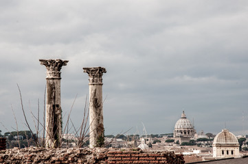 Two ancient columns standing on the top of the wall with ancient Romanian cathedrals on the background