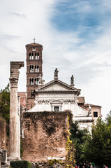 Wall Mural - View on ancient cathedral between the trees with blue cloudy sky on the background