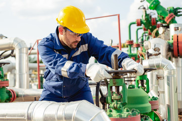 Wall Mural - Oil worker turning valve on oil rig