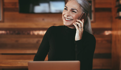 Wall Mural - Senior businesswoman at coffee shop making a phone call