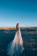 Wall Mural - beautiful bride in a luxurious dress in the desert in the mountains against the background of flying balloons