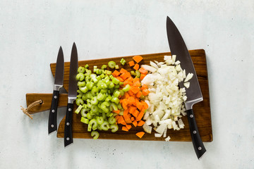 a set of knives on a wooden cutting board and chopped vegetables