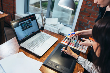 Wall Mural - team of female interior designer drawing a new project using graphic tablet, laptop and color palett
