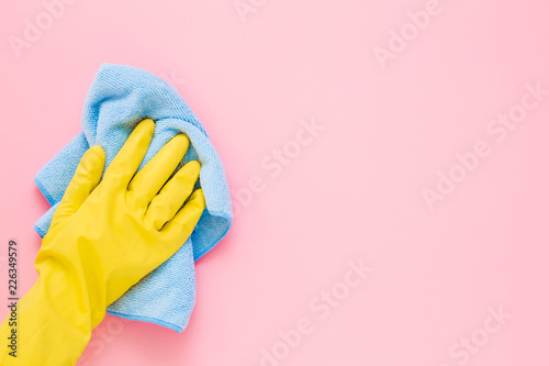 Cuadros en Lienzo Employee hand in yellow rubber protective glove wiping pastel pink wall from dust with blue dry rag