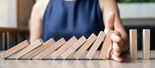 Fotomural Businesswoman hand Stopping Falling wooden Dominoes