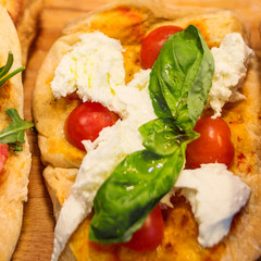 Wall Mural - Italian focaccia with Pepperoni, basil leaf and cheese on a rustic wooden table closeup. Pizza Ready to Eat. Top view