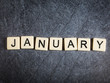 Letter tiles on black slate background spelling January