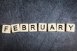 Letter tiles on black slate background spelling February