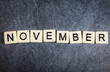 Letter tiles on black slate background spelling November
