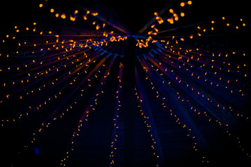 a collection of small little orange lights on the top of a purple ceiling of a tent at a wedding at 