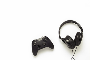 Wall Mural - Black headphones and a gamepad on a white isolated background. Concept of the game on the console or computer. Rest after work. Cybersport. Flat lay, top view