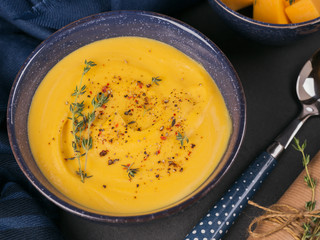 Wall Mural - Pumpkin soup in blue bowl topped with fresh herb