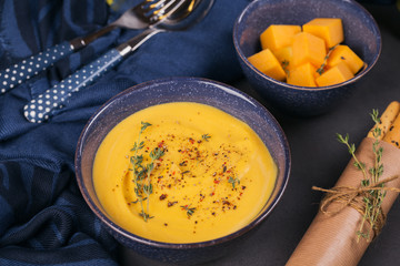 Wall Mural - Pumpkin soup in blue bowl topped with fresh herb