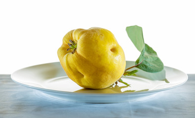 a ripe quince lies on a white plate
