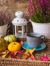 Close Up View Of Vintage Blue Cup Of Coffee In A Tray With Pumpkins And Leaves, Calluna Flowers And A Lantern With A Lit Candle With Wooden Background. Halloween Or Autumn Background