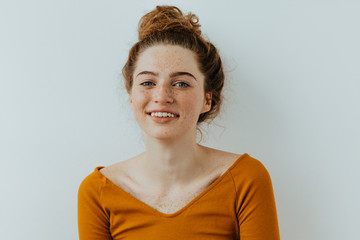 Wall Mural - Woman portrait. Style. Beautiful blue eyed girl with freckles is looking at camera and smiling, on a white background