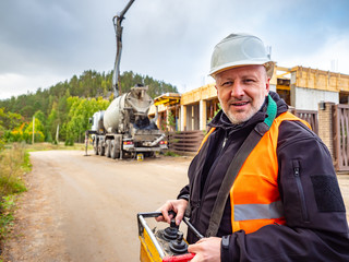 Builder pours concrete. A man in a construction helmet. Cement truck driver. A man controls the supply of cement to the construction site. Engineer. Construction works. looking at the camera.