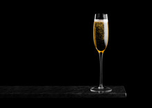 Elegant Glass Of Yellow Champagne With Bubbles On Black Marble Board On Black Background. Space For Text