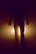 mysterious silhouette of unknown man standing in darkness illuminated from behind by spotlight