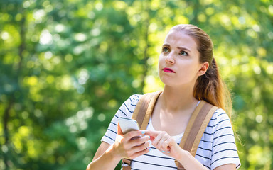 Wall Mural - Young woman using her smartphone on a bright summer day in the forest