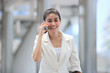 © tuaindeed - Beauty young Asian business woman talk on phone during walking to office.