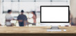 Blank screen desktop computer on wooden table top with blur people working at creative office bokeh background,Mock up for display or montage of design.