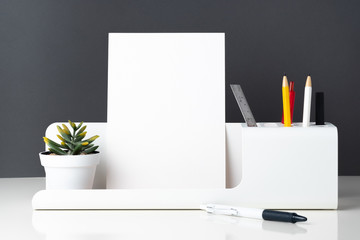 Poster - modern office stationery on white table and dark grey wall.pencil, notepad,ruler,pen and pencil box with plant.Mock up paper note for display of design or content.