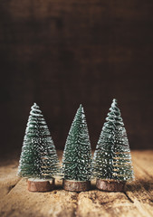 Aufkleber - Three mini christmas tree wood on rustic wooden table and dark brown hardwood wall.winter holiday seasonal greeting card.leave space to adding text or design.