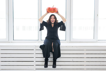 Cute gothic woman in halloween style clothes with pumpkin in hands