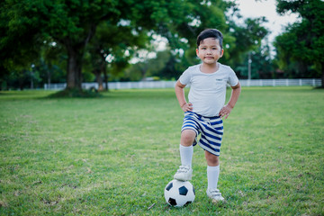 Little Asian child are playing soccer on grass