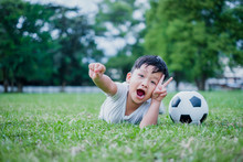 Little Asian Child Playing Football And Celebrating On Grass.