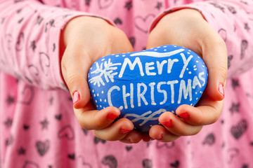 Wall Mural - Young child hands holding blue painted rock with Merry Christmas hand lettering