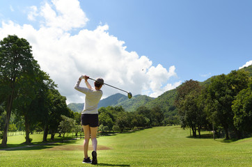 Wall Mural -  Young Asian woman playing golf on a beautiful natural golf course