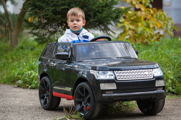 Cute boy in riding a black electric car in the park.