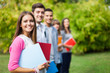 © Minerva Studio - Outdoor portrait of a smiling young student in front of a group of students