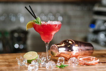 A red cocktail with chopped ice in glass in bar background