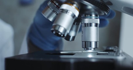 Wall Mural - close-up shot of sample slide and microscope with metal lens at laboratory.