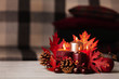 © COLOR PHOTO - Autumn still life - candles, leaves and cones on the background of pillows.