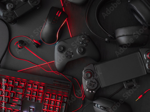 gamer workspace concept, top view a gaming gear, mouse, keyboard, joystick, headset, mobile joystick, in ear headphone and mouse pad on black table background Canvas Print