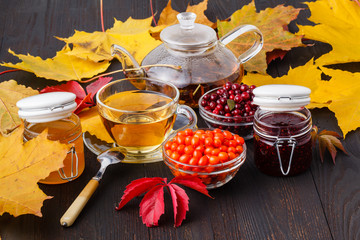 Wall Mural - Vitaminic healthy sea buckthorn tea in small glass tea pot with fresh raw sea buckthorn berries and honey, folk medicina