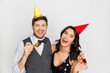 © Syda Productions - birthday, celebration and holidays concept - happy couple with party blowers and caps having fun