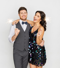 Wall Mural - celebration, fun and holidays concept - happy couple with sparklers at party