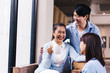 © twinsterphoto - South East Asian senior mother holding a cup of coffee with young man and woman talking with laugh and happiness indoors.