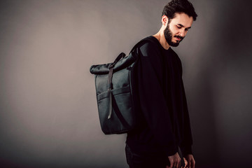 Poster - Stylish young guy wearing black blank  and backpack, horizontal studio portrait