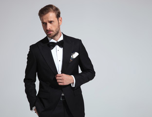 sexy elegant man wearing tuxedo and bowtie posing