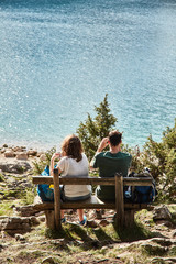 Wall Mural - a young couple sitting on a bench. black lake. durmitor national park. montenegro.