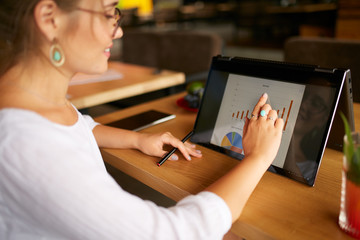 Fototapete - Businesswoman finger touching the chart over convertible laptop screen in tent mode. Freelancer woman using 2 in 1 notebook with touchscreen for work on business presentation. Isolated close view.