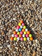 Kunst : Bunte Golfbälle geometrisch (Dreieck) asngeordnet auf Kieselsteinen