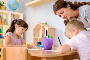 Wall Mural - Preschool teacher assisting children with their drawings. Early education. Harnessing creativity and support.